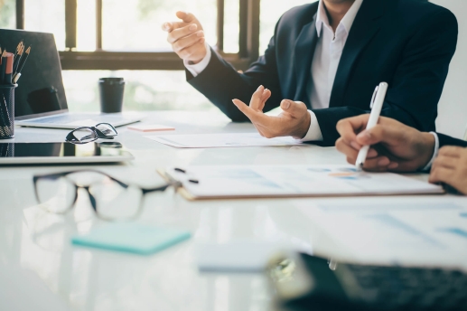 Bürotisch mit diskutierenden Personen und Unterlagen